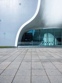 a building with a large curved white facade on it's face near the glass windows