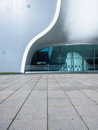 a building with a large curved white facade on it's face near the glass windows