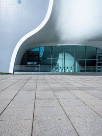a building with a large curved white facade on it's face near the glass windows