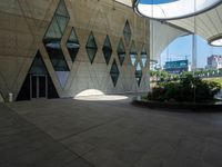 a concrete wall with geometric shaped windows and an open air parking area in front of it