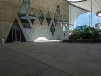 a concrete wall with geometric shaped windows and an open air parking area in front of it