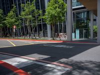 a paved bike lane in the city near tall building with trees outside its windows and red curbs