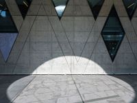 a close up of a building that's on the ground outside of it are multiple triangles of light reflected on the wall