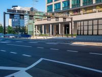 an empty road with a street sign at the curb in front of an office building