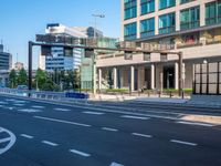 an empty road with a street sign at the curb in front of an office building