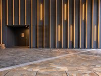 a walkway leading up to a wooden wall next to a cement area with floor tiles