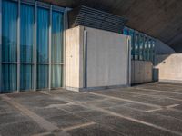 a sidewalk that has several glass doors next to it with buildings in the background behind