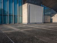 a sidewalk that has several glass doors next to it with buildings in the background behind