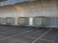 two empty parking spaces with two empty doors and a large window on the wall between two buildings