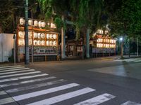 a street with several rows of lamps on either side of the road, two people crossing over a street