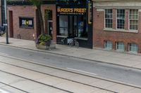 a man on a bike passes a burgers frisbee shop on a city street