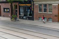 a man on a bike passes a burgers frisbee shop on a city street