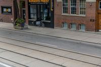 a man on a bike passes a burgers frisbee shop on a city street