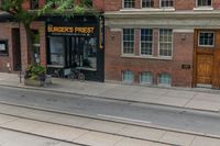 a man on a bike passes a burgers frisbee shop on a city street