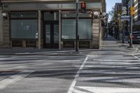 a couple of people riding on a sidewalk next to a building with windows and traffic lights