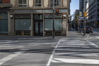 a couple of people riding on a sidewalk next to a building with windows and traffic lights