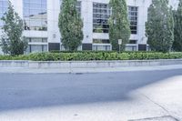 a car driving down an empty street lined with tall buildings and trees in the background