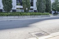 a car driving down an empty street lined with tall buildings and trees in the background