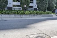 a car driving down an empty street lined with tall buildings and trees in the background