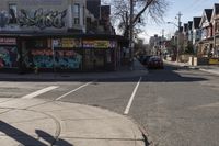 two lanes of a street with multiple stores on one side of the road and trees and buildings in the other direction