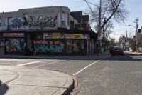 two lanes of a street with multiple stores on one side of the road and trees and buildings in the other direction