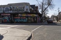 two lanes of a street with multiple stores on one side of the road and trees and buildings in the other direction