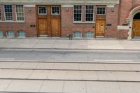 two buildings are behind a row of stairs and an empty sidewalk with tracks of traffic