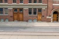 two buildings are behind a row of stairs and an empty sidewalk with tracks of traffic