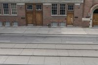 two buildings are behind a row of stairs and an empty sidewalk with tracks of traffic