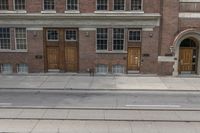 two buildings are behind a row of stairs and an empty sidewalk with tracks of traffic