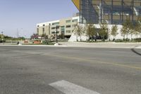 an empty street with a bus stop sign on it in front of a building,