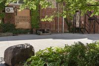 a brick building with a sign in front of a tree and stairs leading to a room