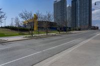 an empty street with several buildings along side of it on either side are bushes and shrubs