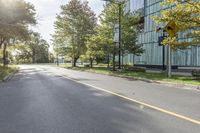 this is the view on an empty street from a corner near some trees and a building