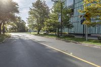 this is the view on an empty street from a corner near some trees and a building