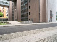 the empty sidewalk on the side of the street near the building in the city is cobblestone