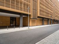 this is an exterior of a building, which has wood cladding along the side, with pillars and windows, on either side a street