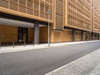 this is an exterior of a building, which has wood cladding along the side, with pillars and windows, on either side a street