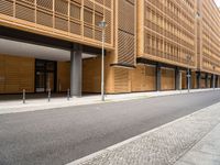 this is an exterior of a building, which has wood cladding along the side, with pillars and windows, on either side a street