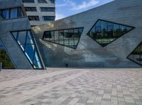 a blue fire hydrant sitting next to a large building with many windows and triangles on the side