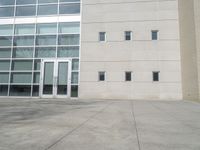 an outdoor area with a parking lot, a large building and glass windows next to it