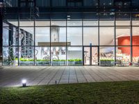 an outdoor area with grass and windows lit up at night with a bicycle parked in the middle