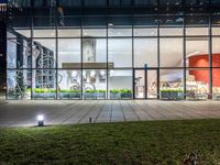 an outdoor area with grass and windows lit up at night with a bicycle parked in the middle