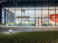 an outdoor area with grass and windows lit up at night with a bicycle parked in the middle