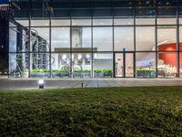 an outdoor area with grass and windows lit up at night with a bicycle parked in the middle