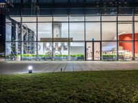 an outdoor area with grass and windows lit up at night with a bicycle parked in the middle