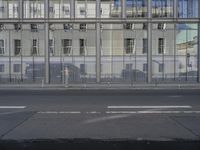 a large building is reflected in the side of the street that goes along this narrow road