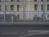 a large building is reflected in the side of the street that goes along this narrow road