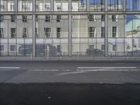 a large building is reflected in the side of the street that goes along this narrow road