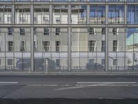 a large building is reflected in the side of the street that goes along this narrow road